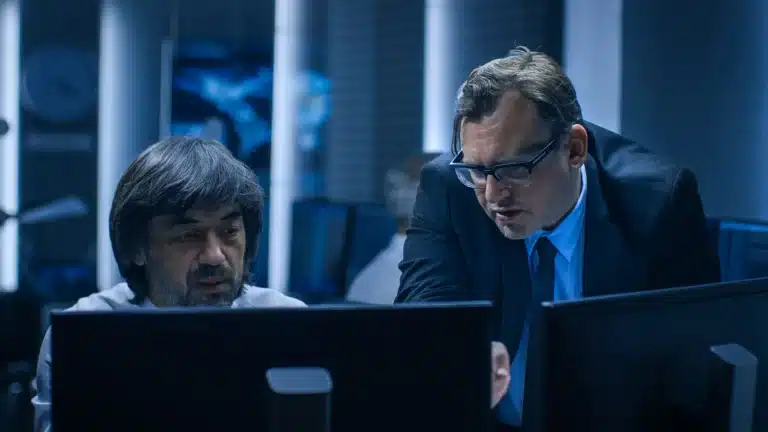 Two men in a reviewing information on a computer screen